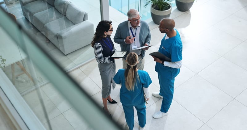 Group of doctors, admin and nurses having a conversation shown from a floor above