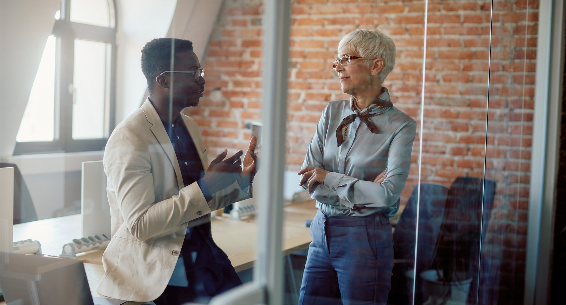 Black male and white female coworkers talking in conference room