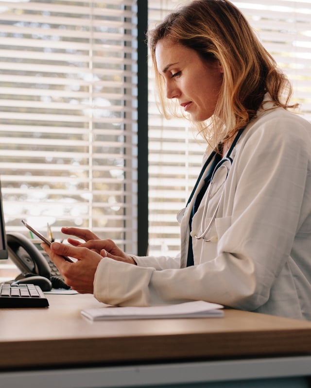 Female physician on her phone in her office