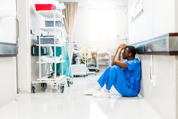 Sad male African American physician or nurse sitting in hallway_small