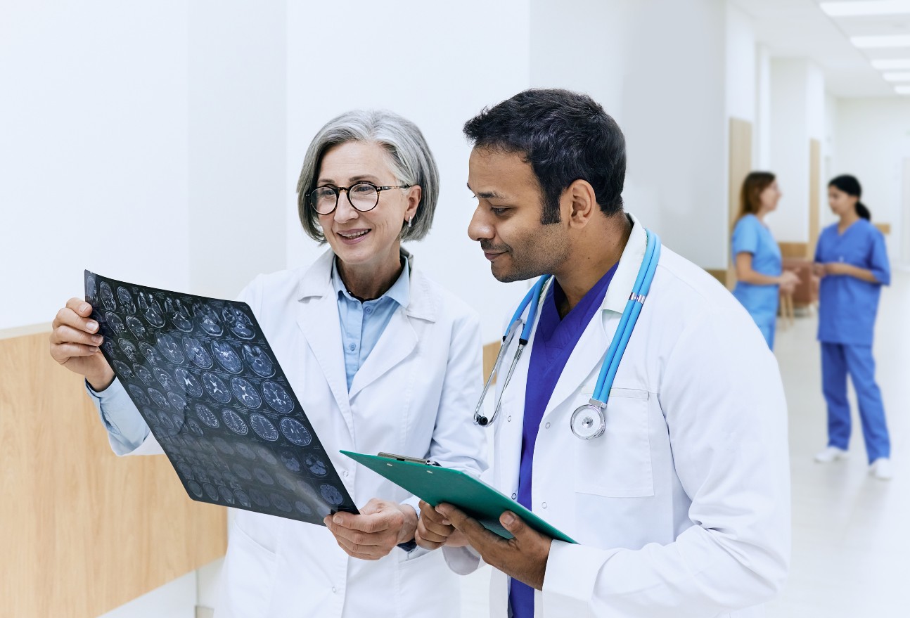 Two doctors analyzing MRI scan of patients brain and diagnosing illness while standing in corridor 